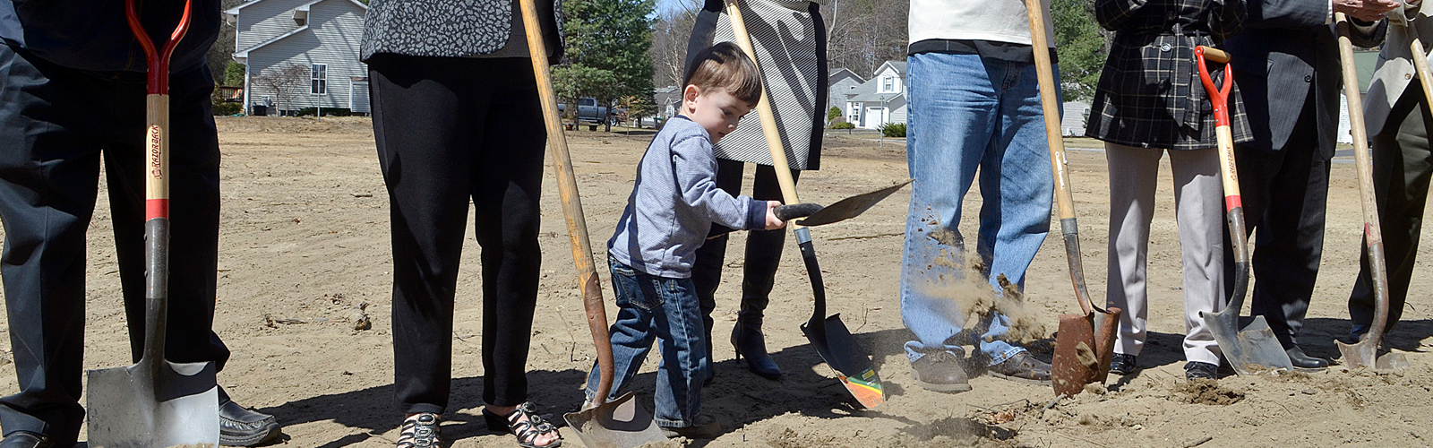 Image of three adults and one child breaking ground