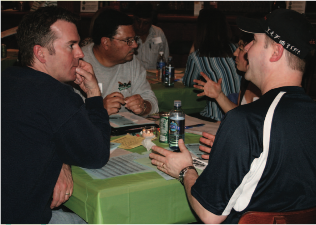 A small group sits at a table engaging in community conversation
