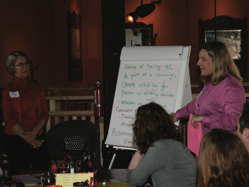 Community conversation organizers engage a group with an oversized notepad