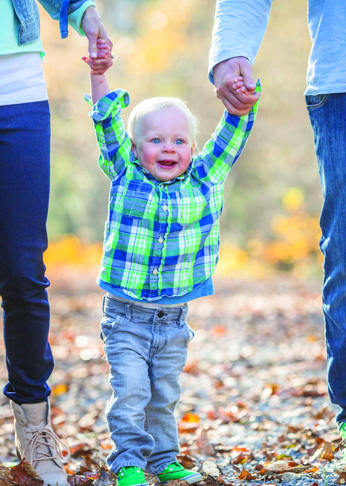 boy holding onto both parents hands as he walks