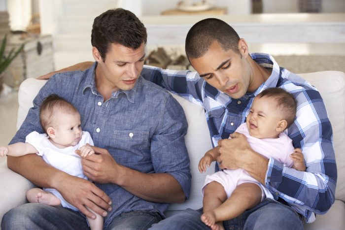 Two dads holding their children on their laps.